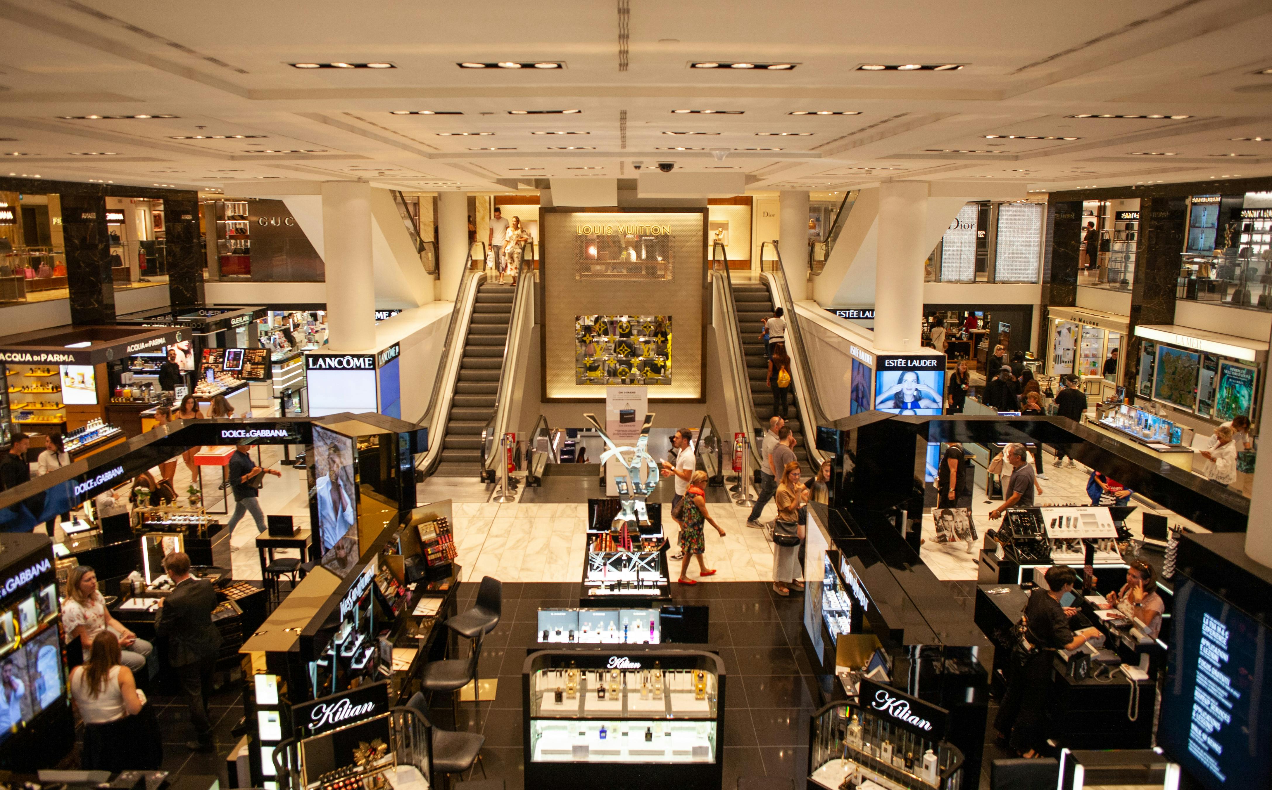 Busy retail mall interior with shoppers walking through stores